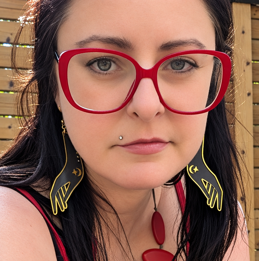  woman wearing black and gold laser engraving earrings  of hands,made from 2 tone black gold acrylic from Local Laser Supply